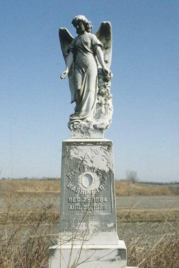 Angel statue on a pedestal, set against a clear blue sky.