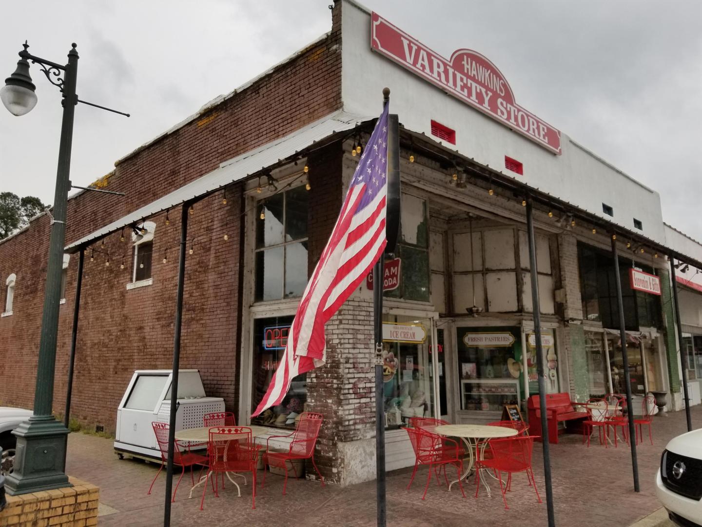 Vintage store with an American flag and red outdoor furniture.