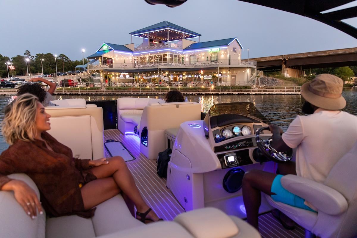Boat on water near a lit-up waterfront restaurant at dusk.