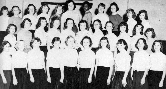 Black and white photo of a group of women in rows, wearing matching attire.