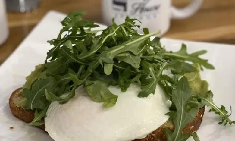 Poached egg and arugula on toast, on a white plate.
