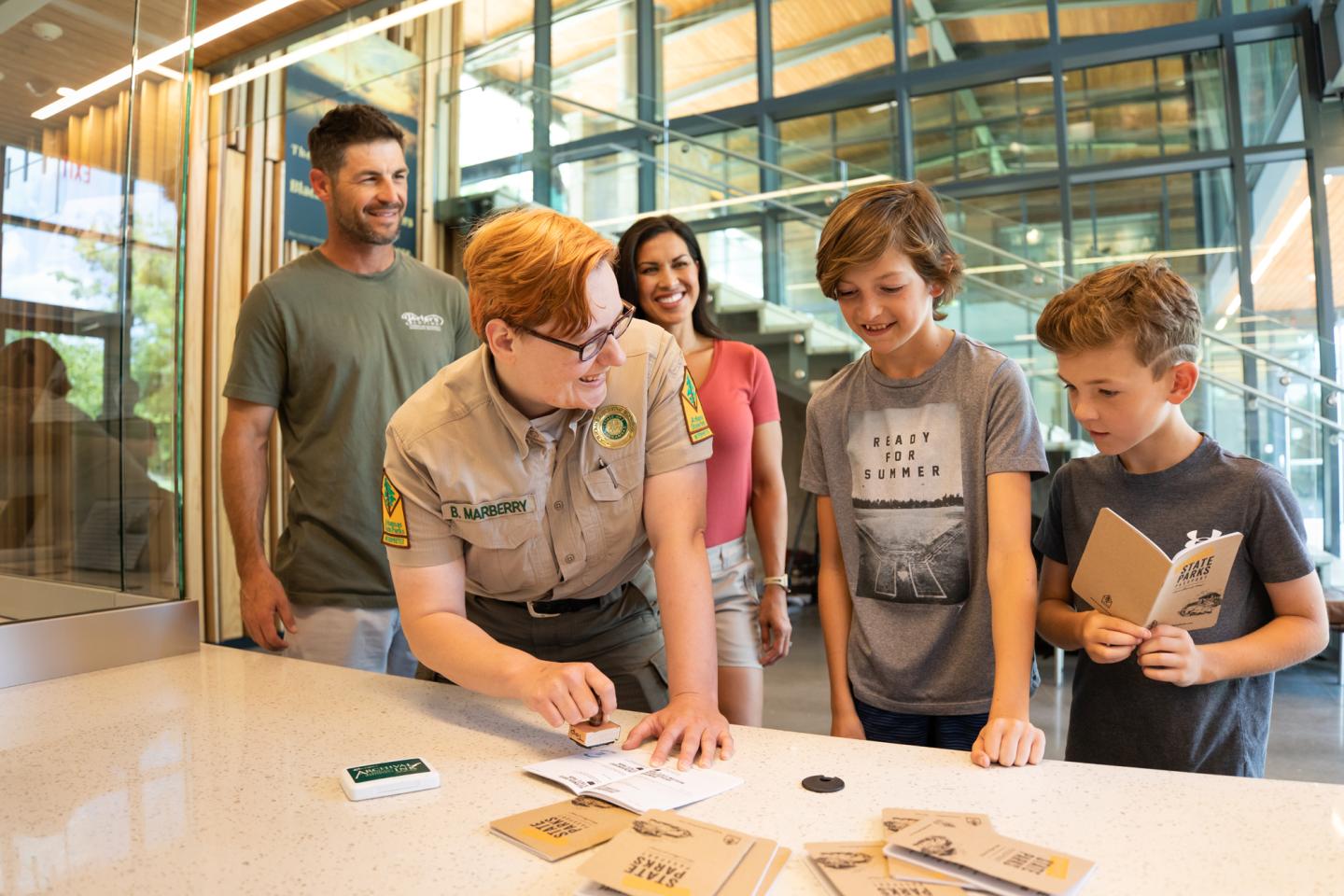 Group at a desk with park ranger, children, and parents smiling.