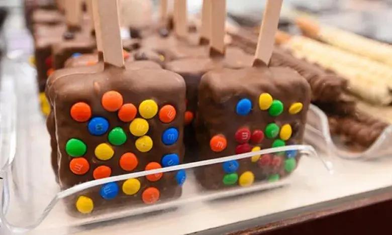 Chocolate pops with colorful candy coating displayed in a tray.