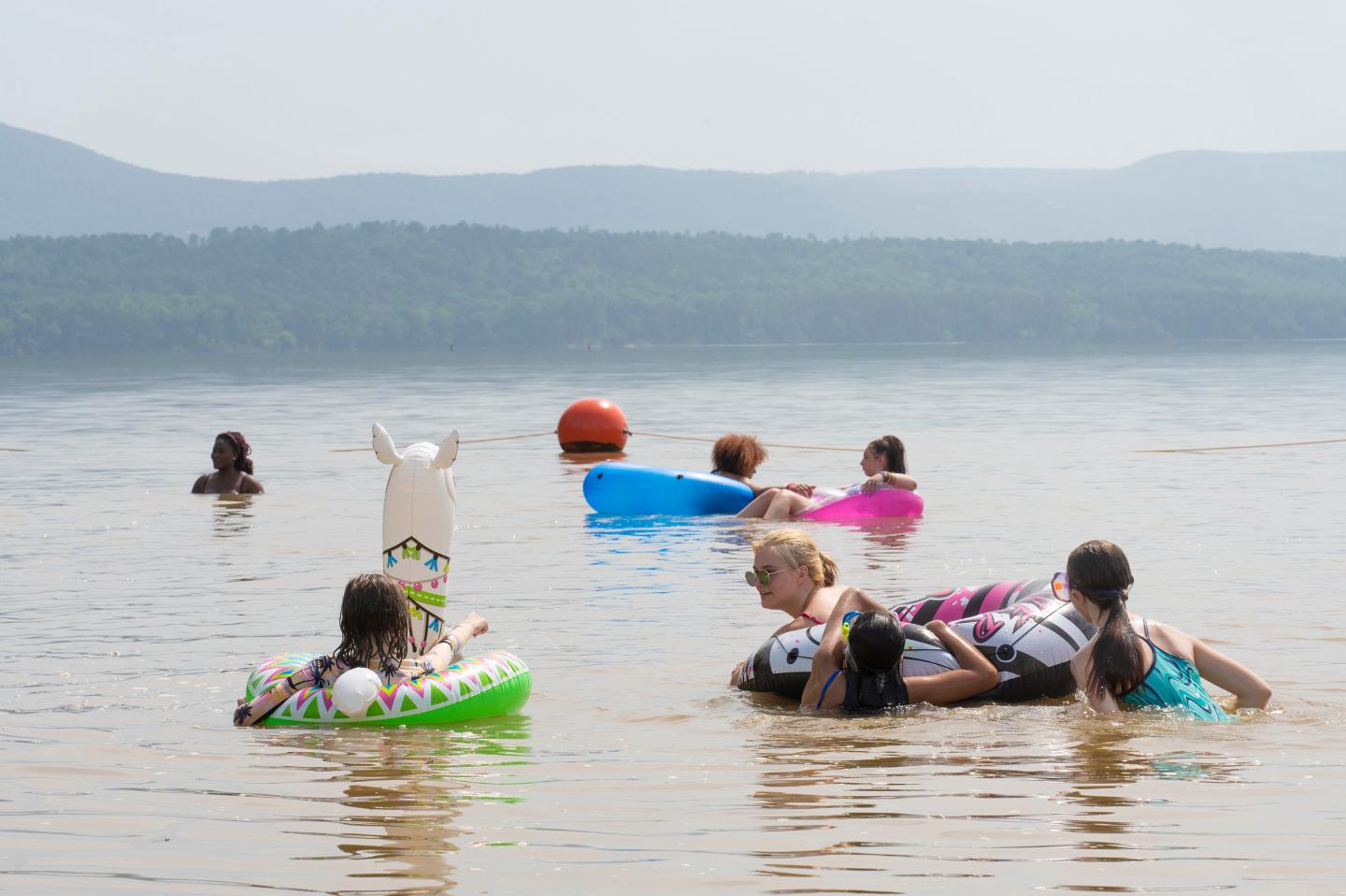 People floating on lake with inflatables on a sunny day.