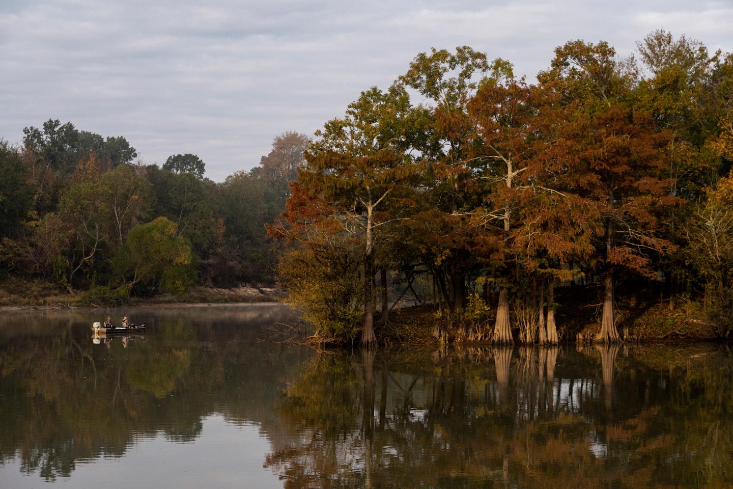 Calm lake with autumn trees reflecting on water.