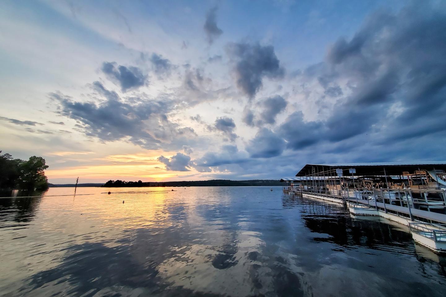 Sunset over a lake with docks and vibrant clouds reflecting on the water.