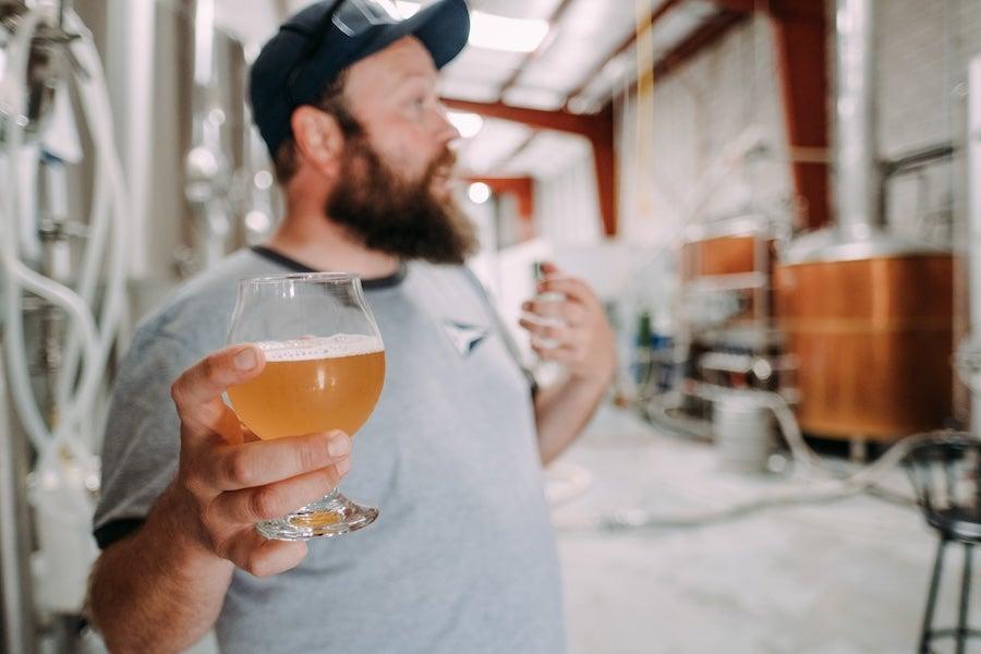 Man holding a glass of beer in a brewery.