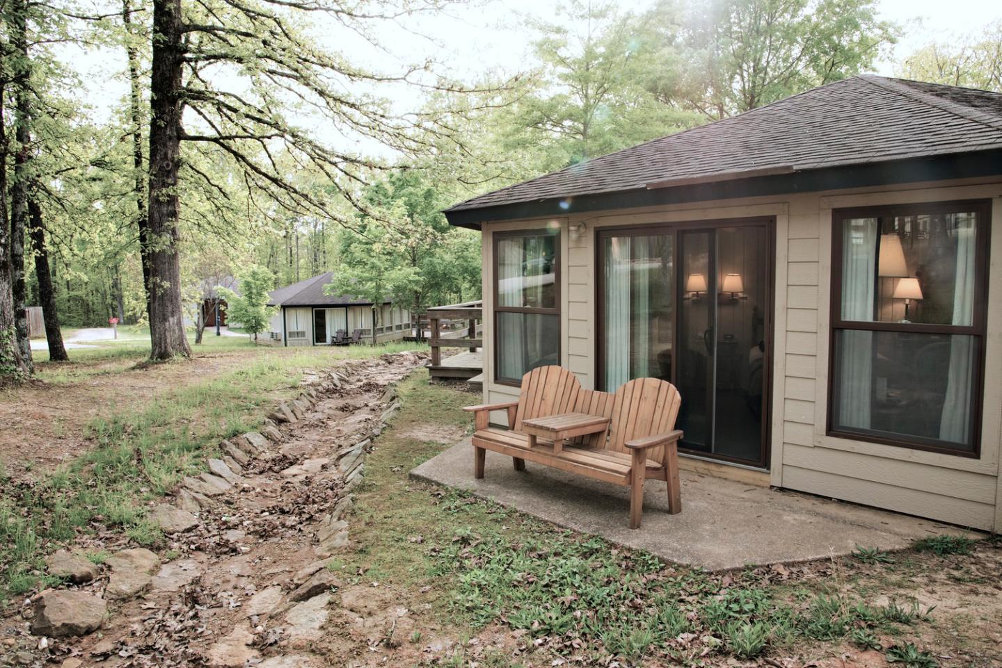 Cabin with a porch and chairs in a wooded area.