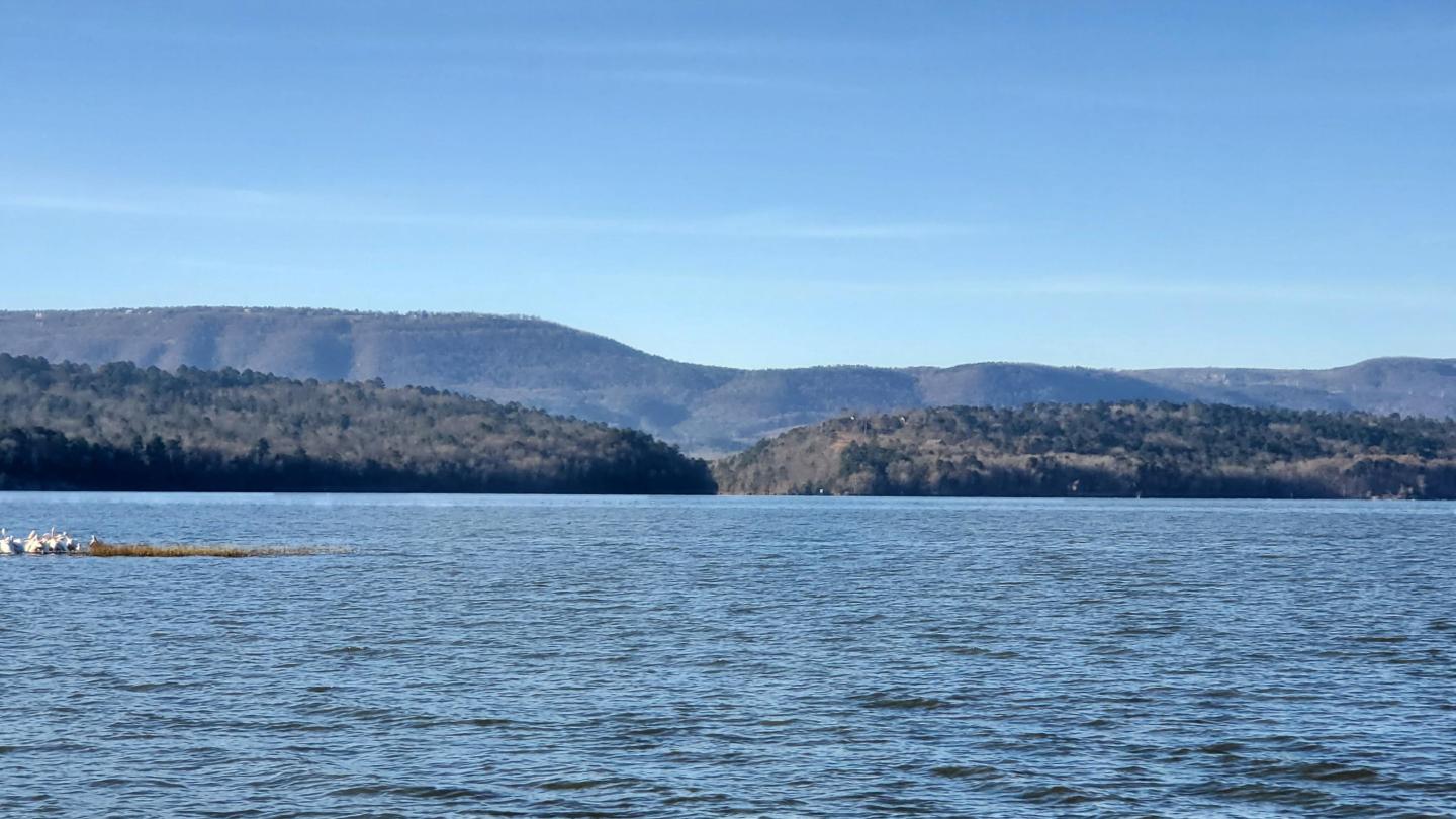Calm lake with distant hills under a clear blue sky.