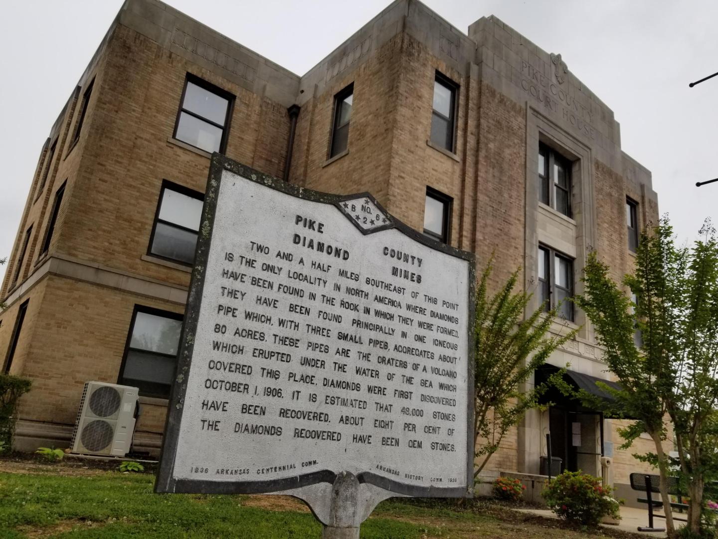 Historic building with a plaque in front, overcast sky.