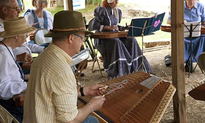 People playing dulcimers at an outdoor gathering.
