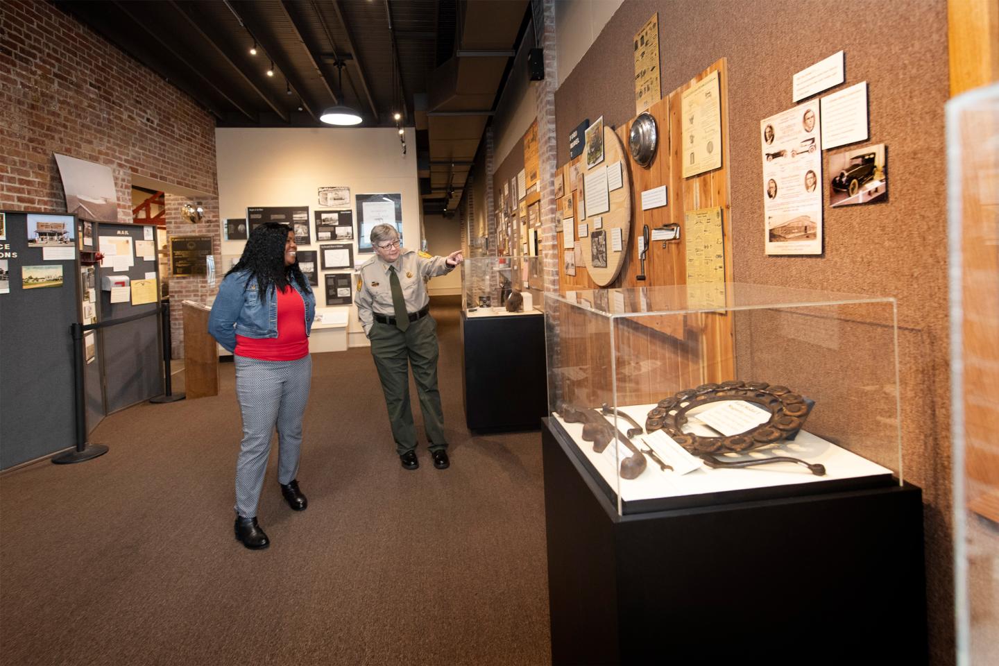 Museum guide showing exhibits to a visitor in a gallery setting.