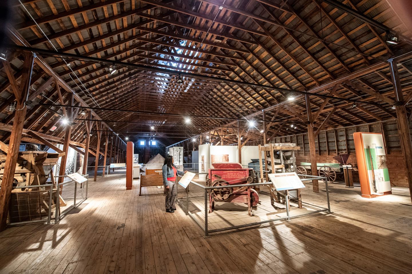 Historic barn interior with exhibits and wooden beams.