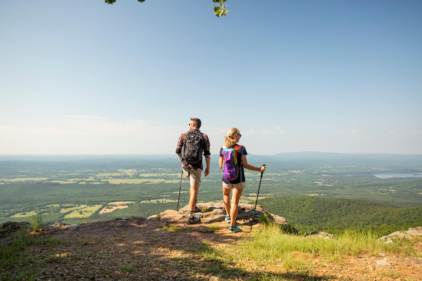 Hikers with backpacks enjoy a scenic mountain view under a clear blue sky.