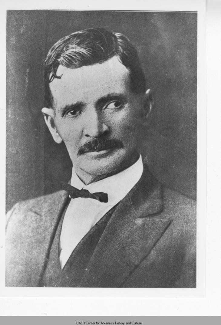 Black and white portrait of a man in a suit with a mustache.