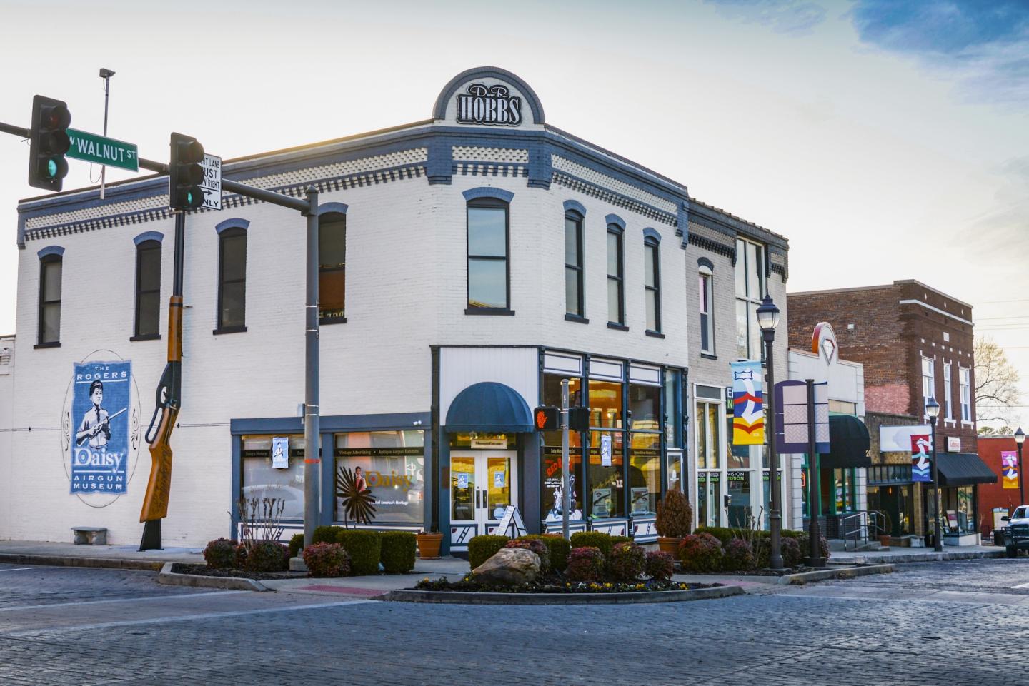 Historic corner building with shops and street signs in a small town setting.