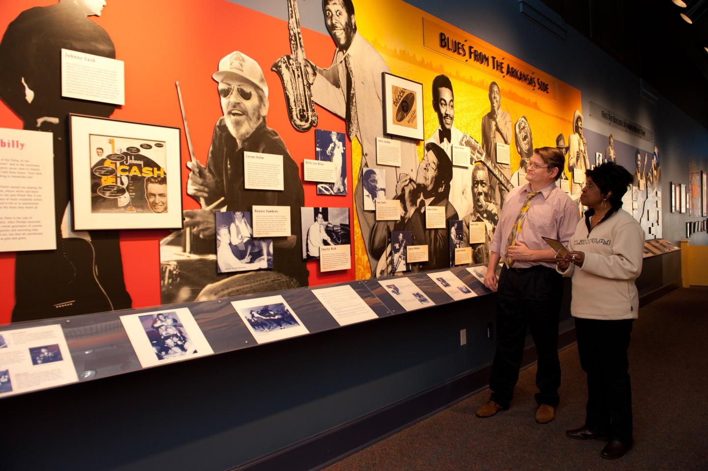Two people observe a colorful museum photo exhibit.