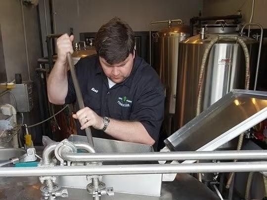 Man stirring mixture in a brewing tank.