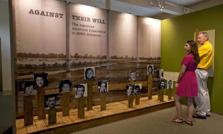 Exhibit with photos on wooden stands, two people observing.