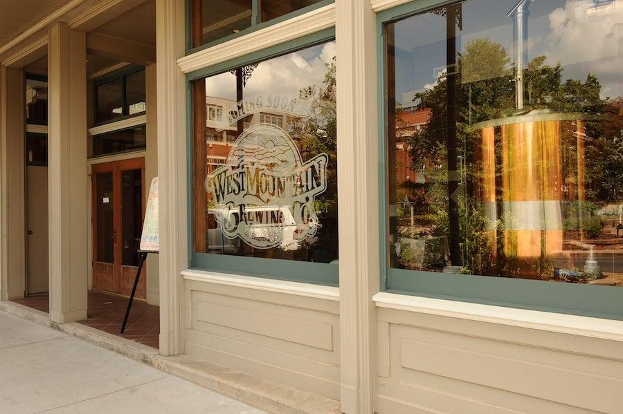 Storefront with large windows, reflections of trees, and a sidewalk view.