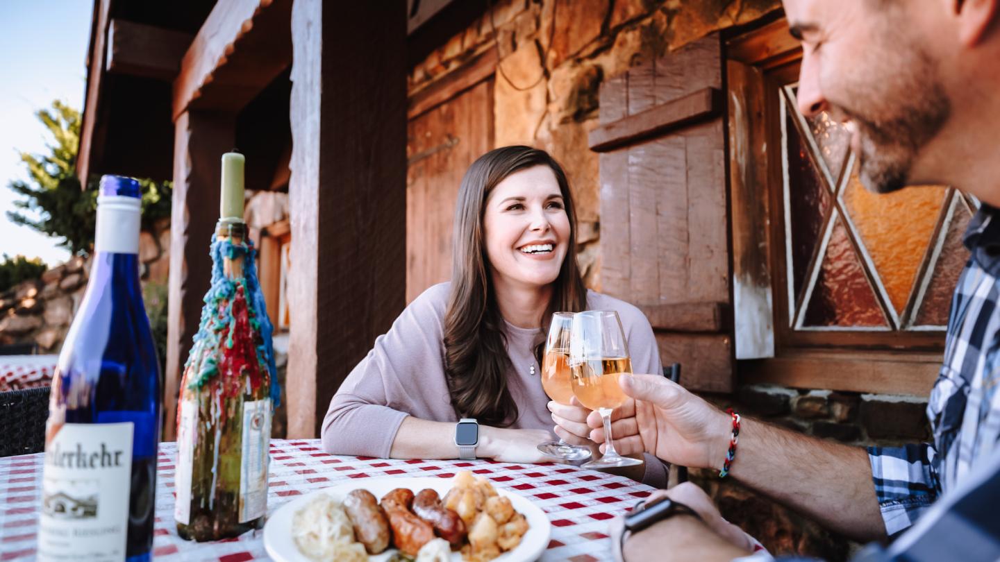 Couple enjoying wine and charcuterie at rustic outdoor cafe.
