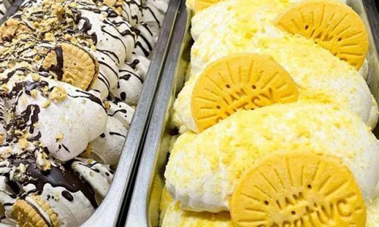 Two tubs of ice cream: one with chocolate drizzle and cookies; the other with citrus slices.