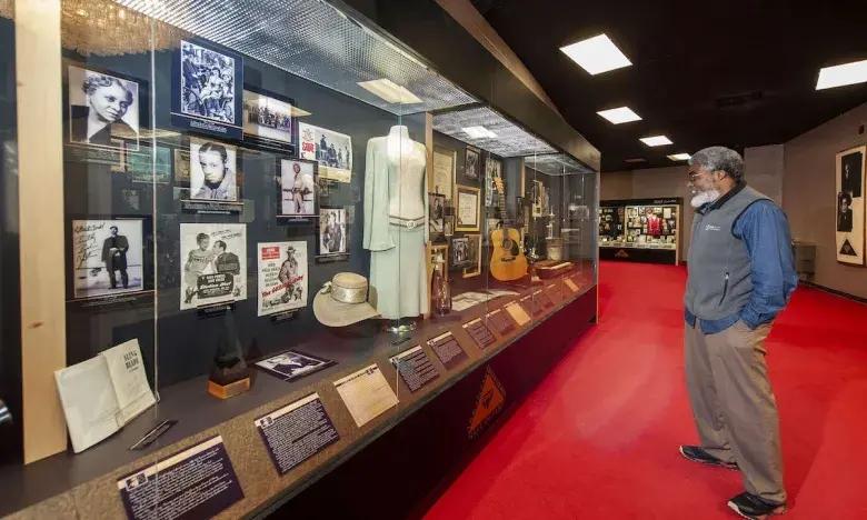 Museum exhibit with memorabilia on display, person observing behind glass.