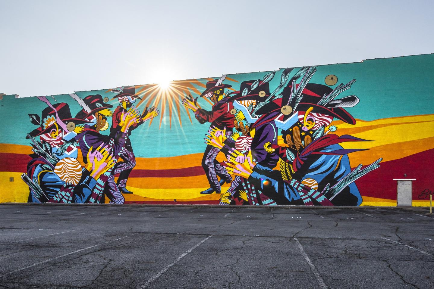 Colorful mural with abstract figures and geometric patterns under bright sunlight.