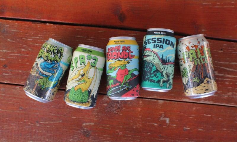 Five colorful beer cans on a wooden table.