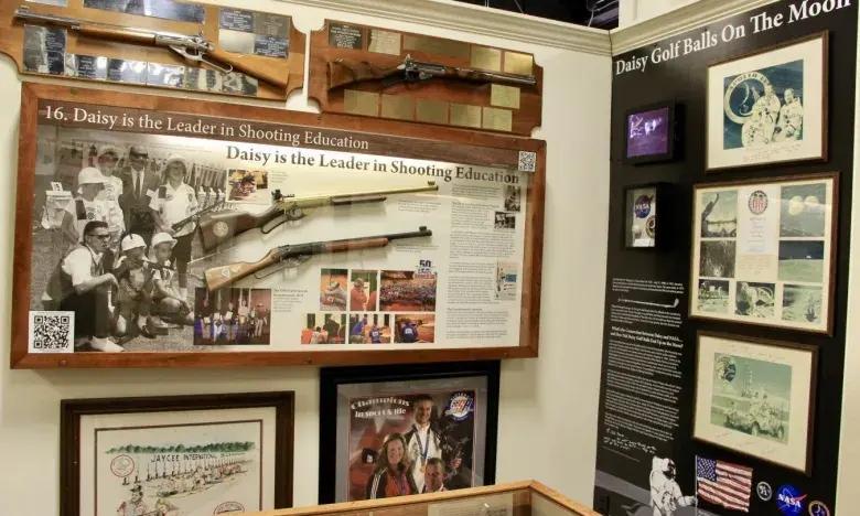 A display case featuring historic rifles, photographs, and informational panels.