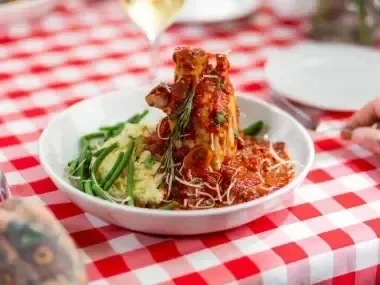 Pasta dish with tomato sauce, green beans, and mashed potatoes on a checkered tablecloth.