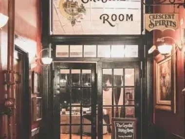 Entrance to a warmly lit bar with a vintage sign above.