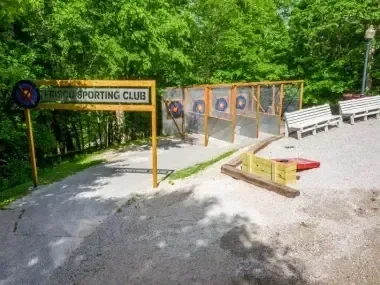 Archery range with target boards surrounded by lush green trees.