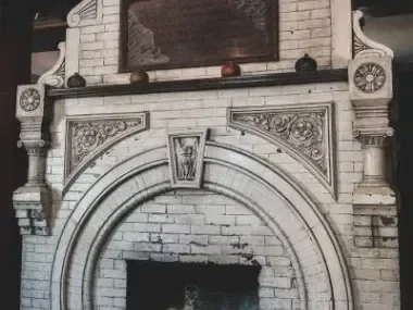 Ornate white brick fireplace with decorative carvings and a dark firebox.