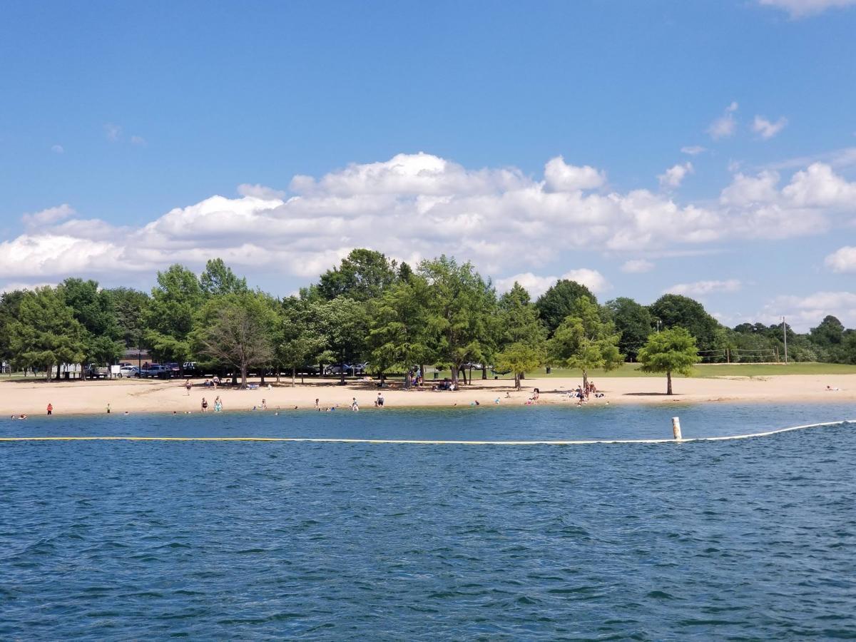 Beach with trees and people under a blue sky with clouds.