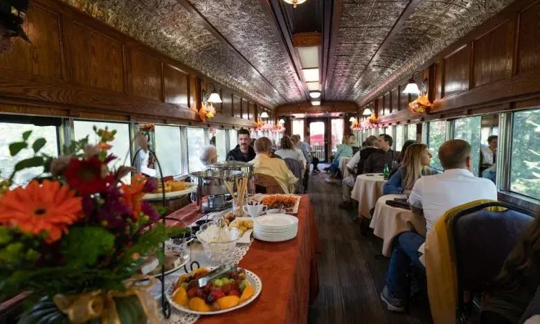 Elegant dining area inside a vintage train, with tables set and passengers seated.