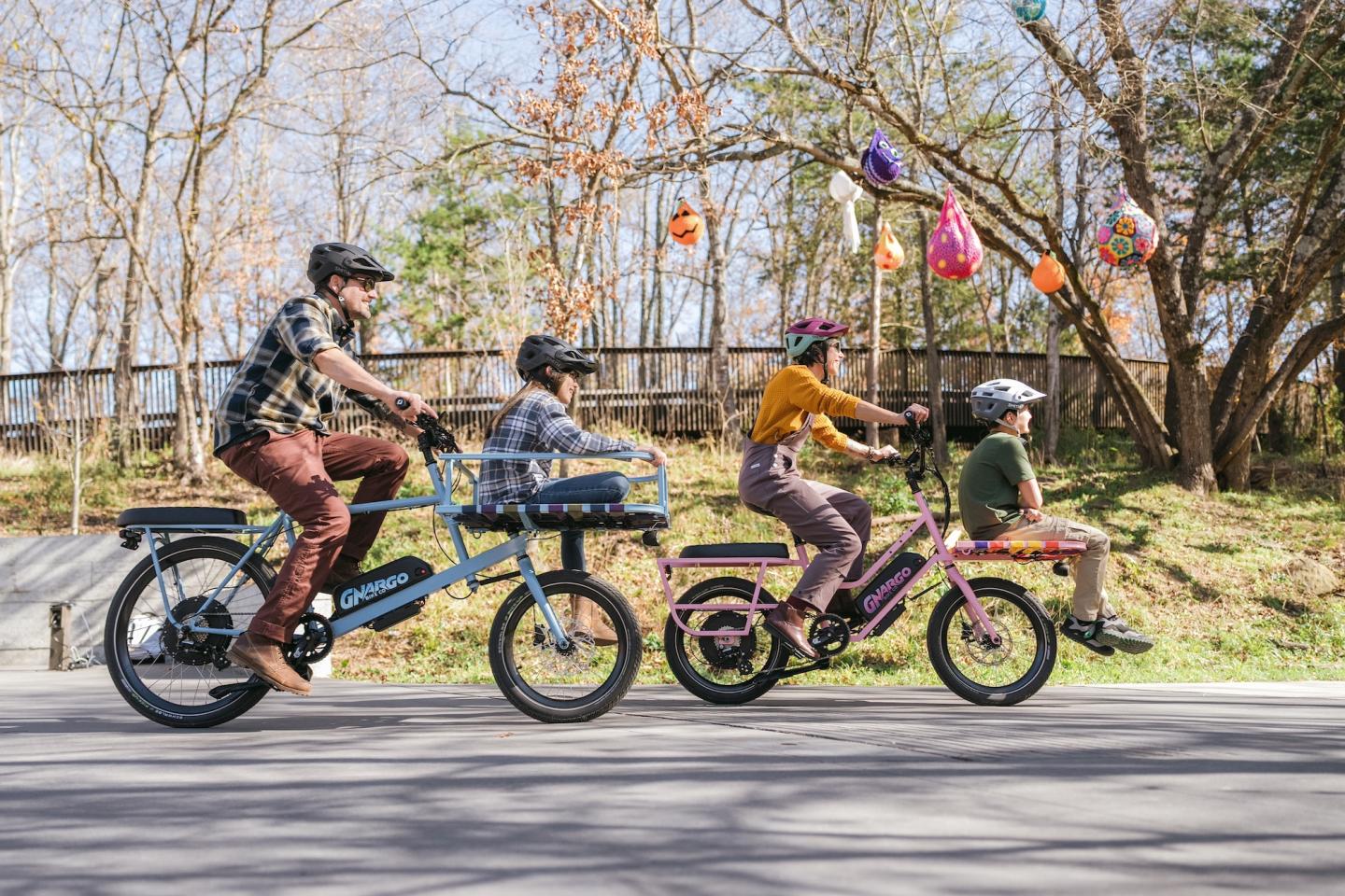 Two adults and a child on bicycles riding on a paved path in a park.