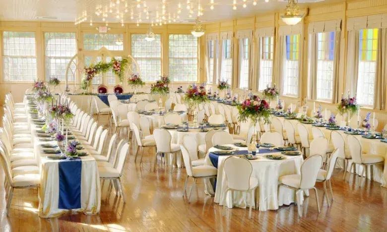 Elegant banquet hall with decorated round tables and chairs.