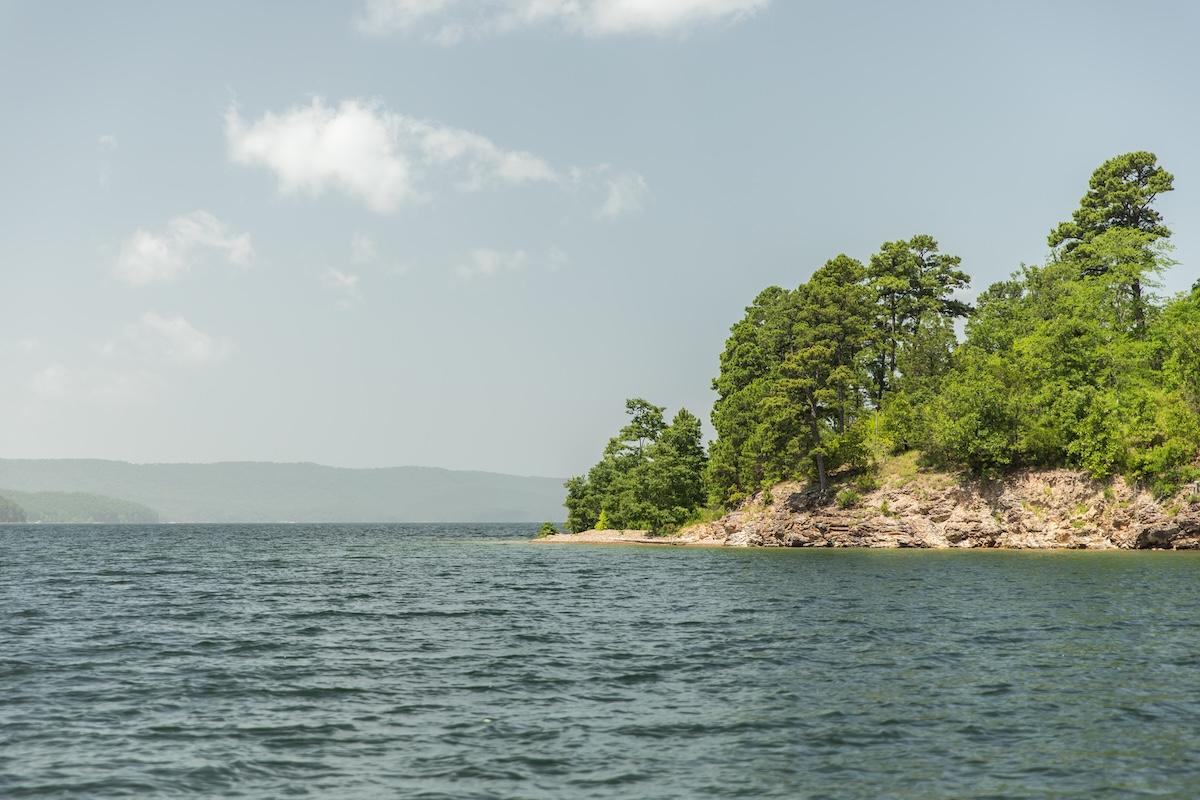 Calm lake with tree-lined shoreline under a clear sky.