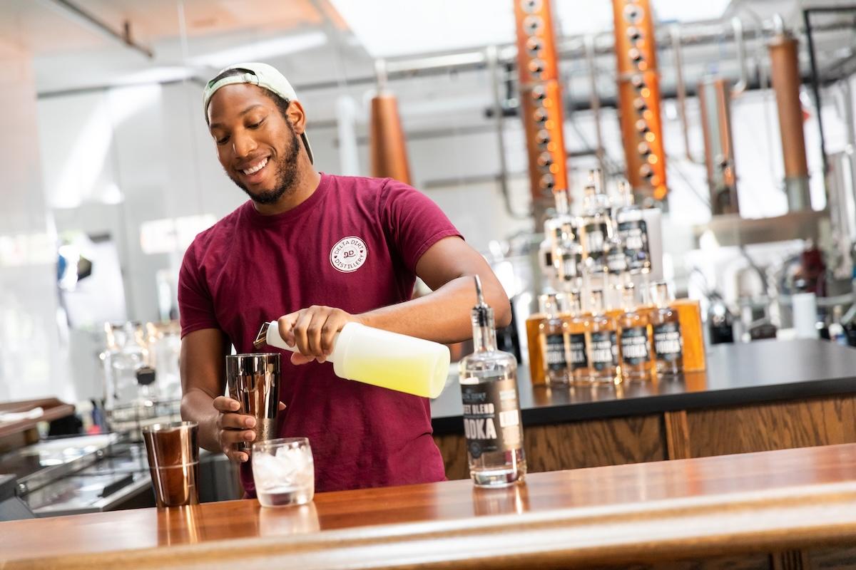 Bartender in a red shirt mixing drinks at a modern bar.