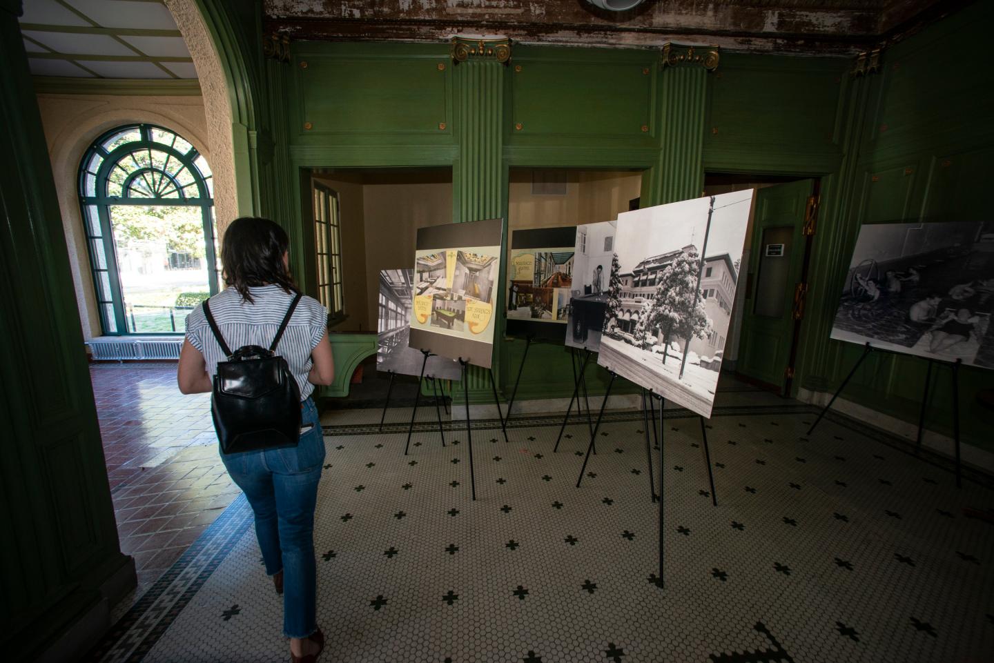 A person walks through an art gallery with paintings on easels.