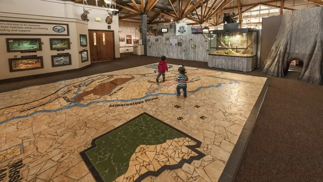 Museum exhibit with large floor map, two children walking across it.