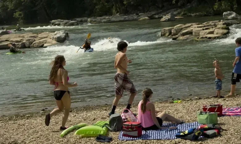 People relaxing and playing by a rocky riverbank.