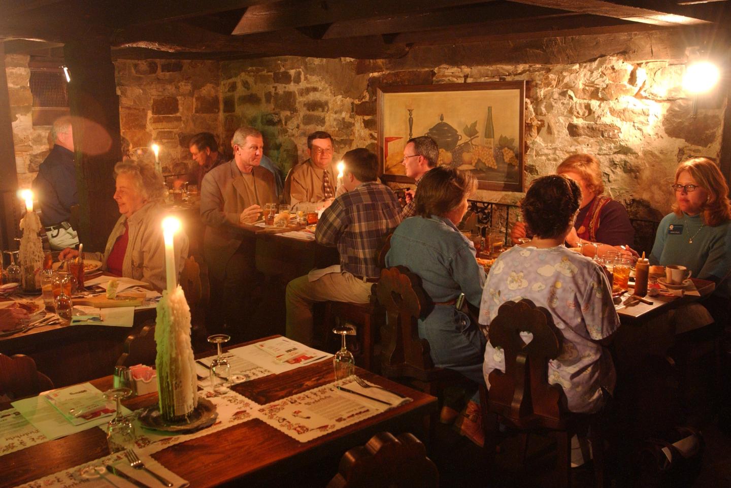 Candlelit group dinner in a cozy, rustic restaurant setting.