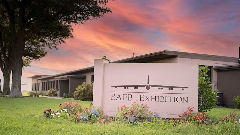 Building with a sign in front, sunset sky.