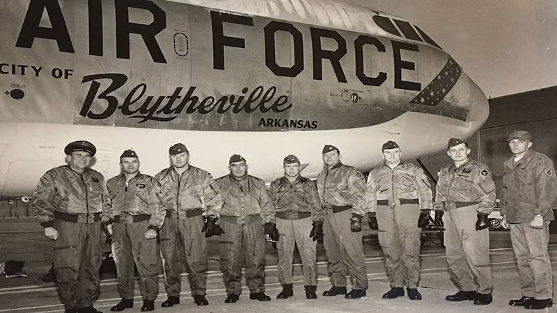 Black and white photo of nine airmen standing in front of an Air Force aircraft.