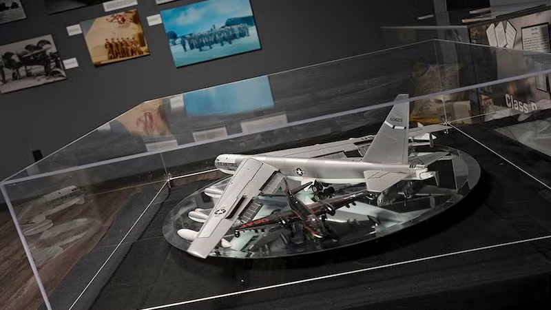 Aircraft model in a glass display case with photo wall background.