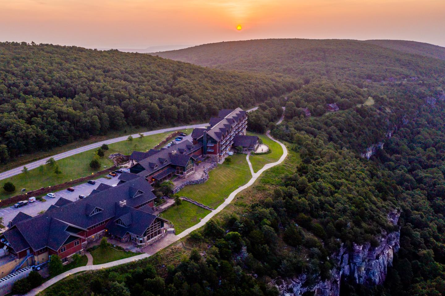 Aerial view of Mount Magazine lodge on a forested hillside at sunset.