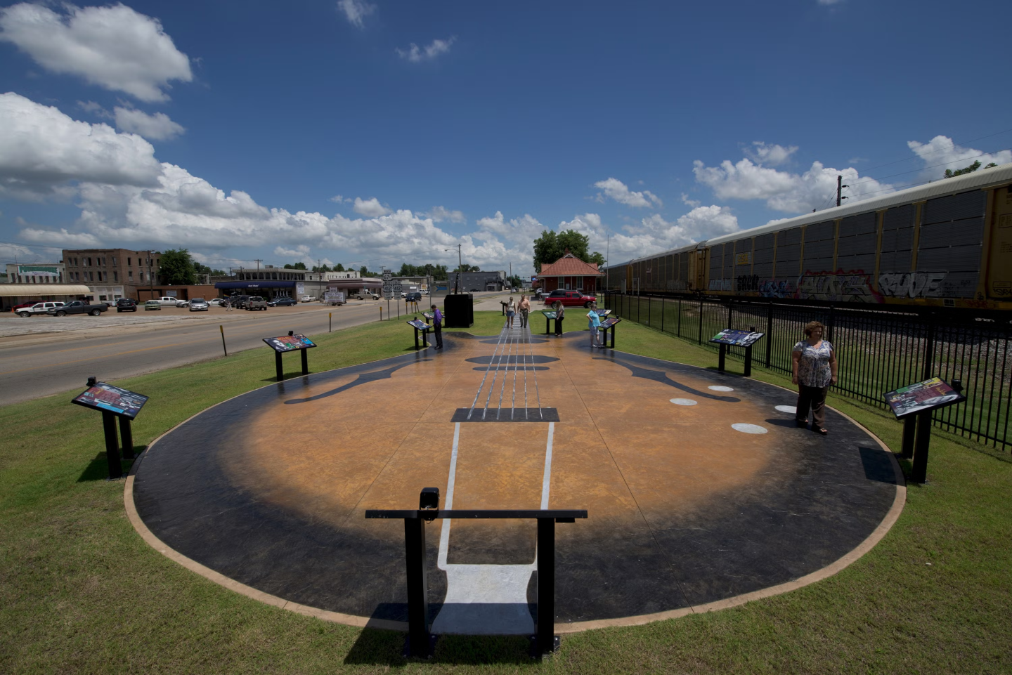 Baseball field sculpture with informational signs under a clear blue sky.
