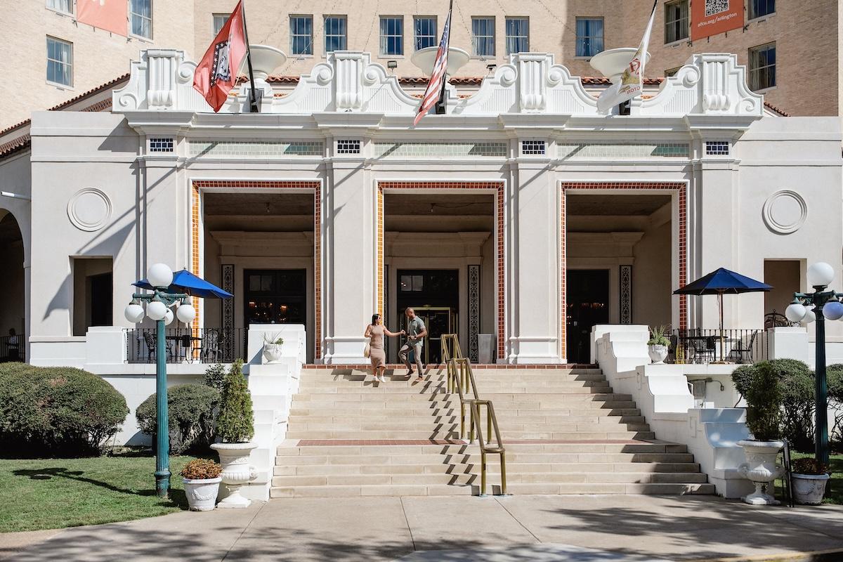Grand hotel entrance with flags and stairs under a clear sky.